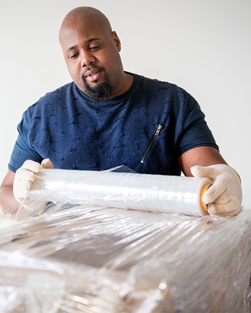 adult male wrapping boxes in clear wrap to secure the boxes